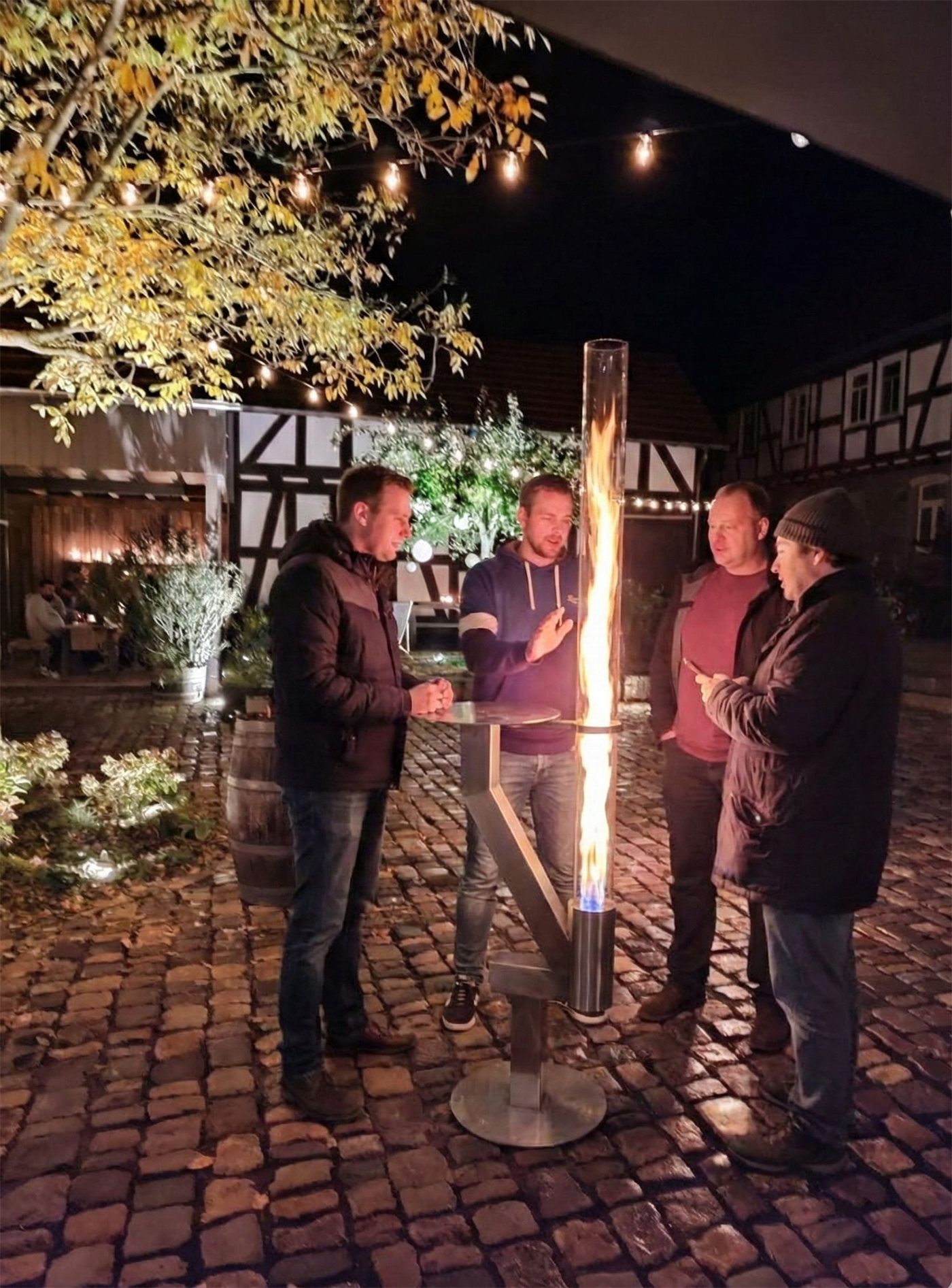 Gäste stehen abends gesellig um die Rhönfackel